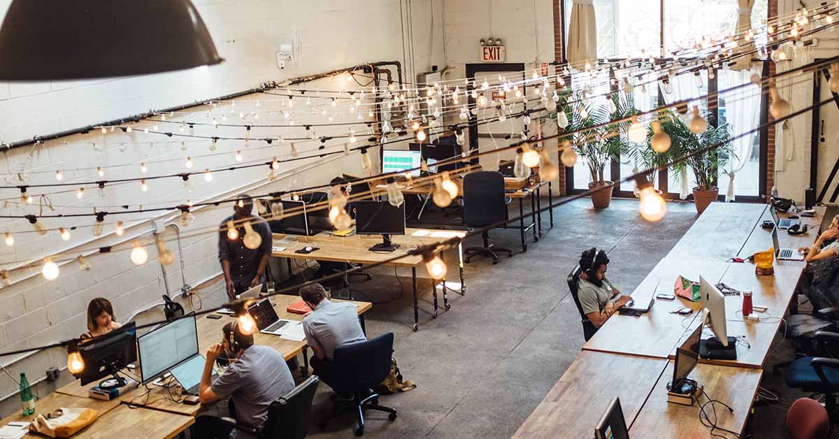 Cozy modern office space with hanging lights and people working