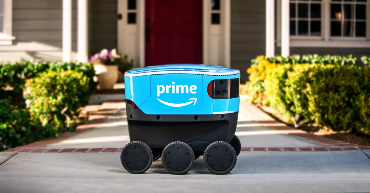 Delivery robot on a sidewalk in front of a house displaying a company logo