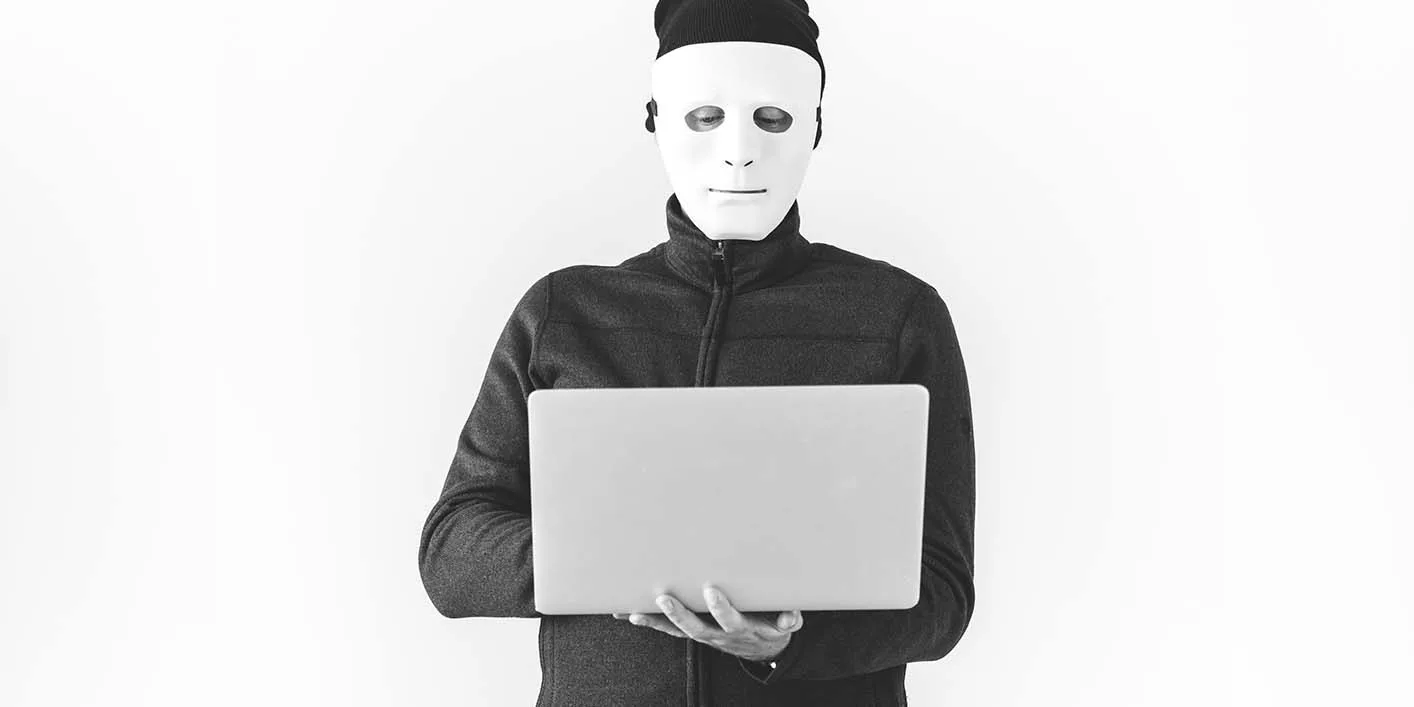 Person in mask holding laptop against white background