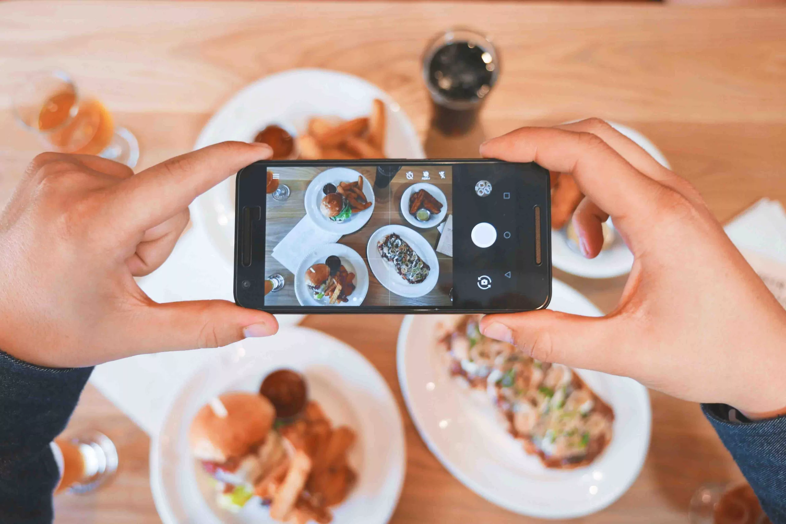 Person taking photo of gourmet food on table with smartphone
