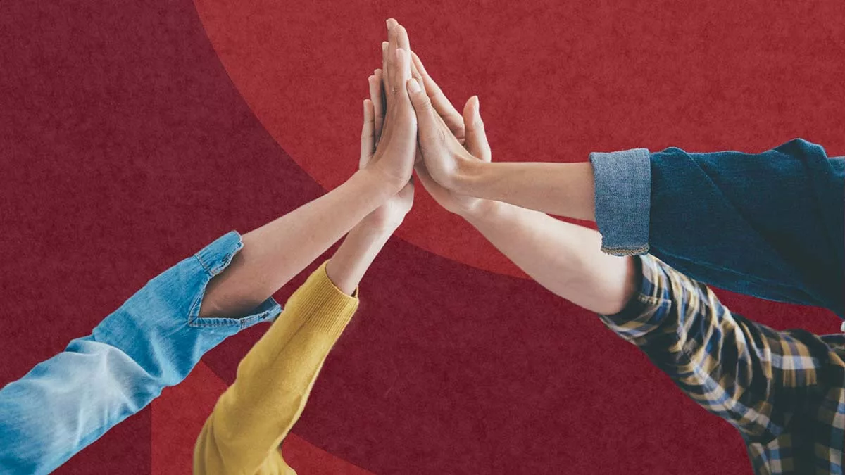 Three people performing a high five on a red background