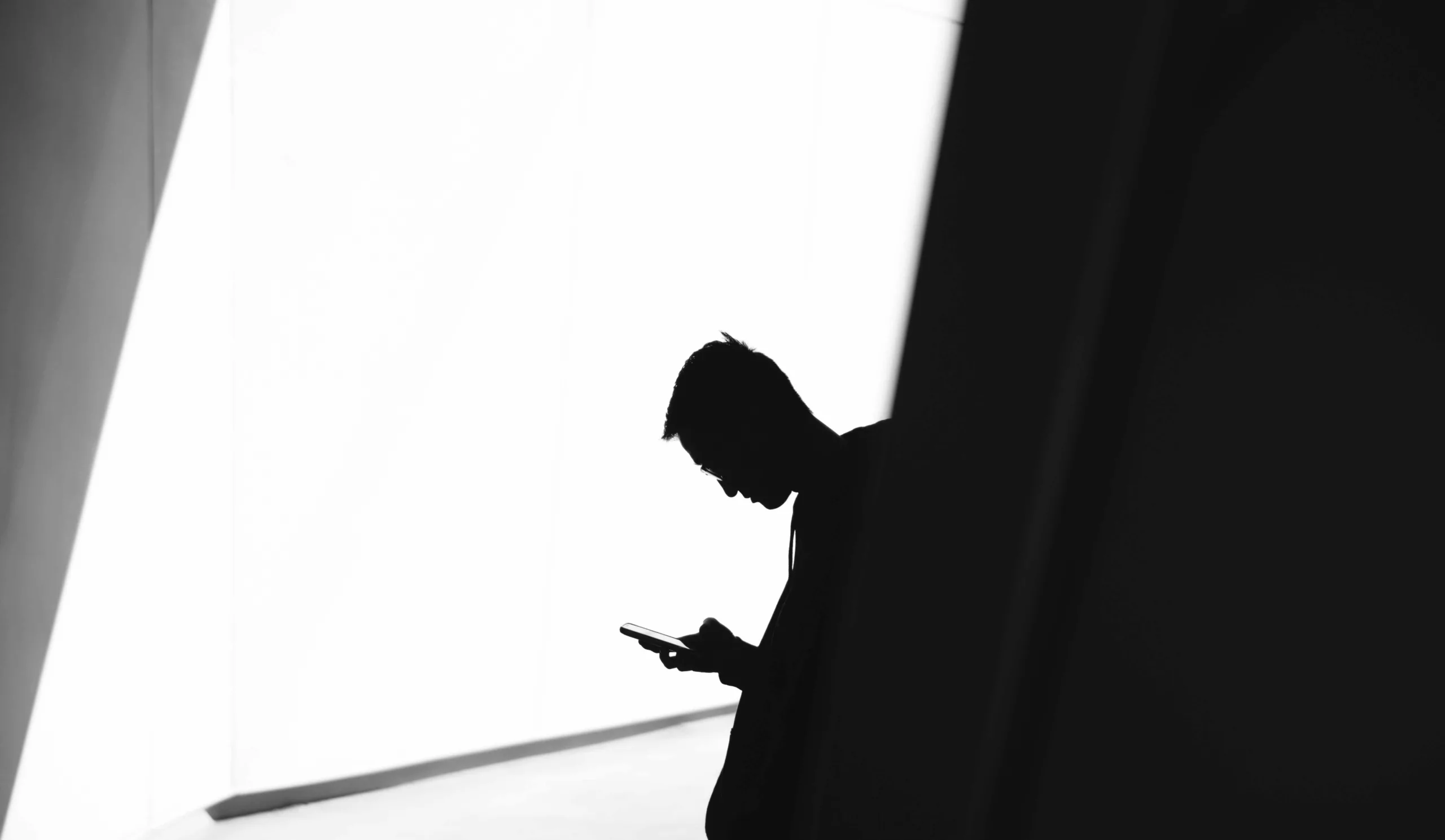 Silhouetted person using smartphone in high contrast black and white