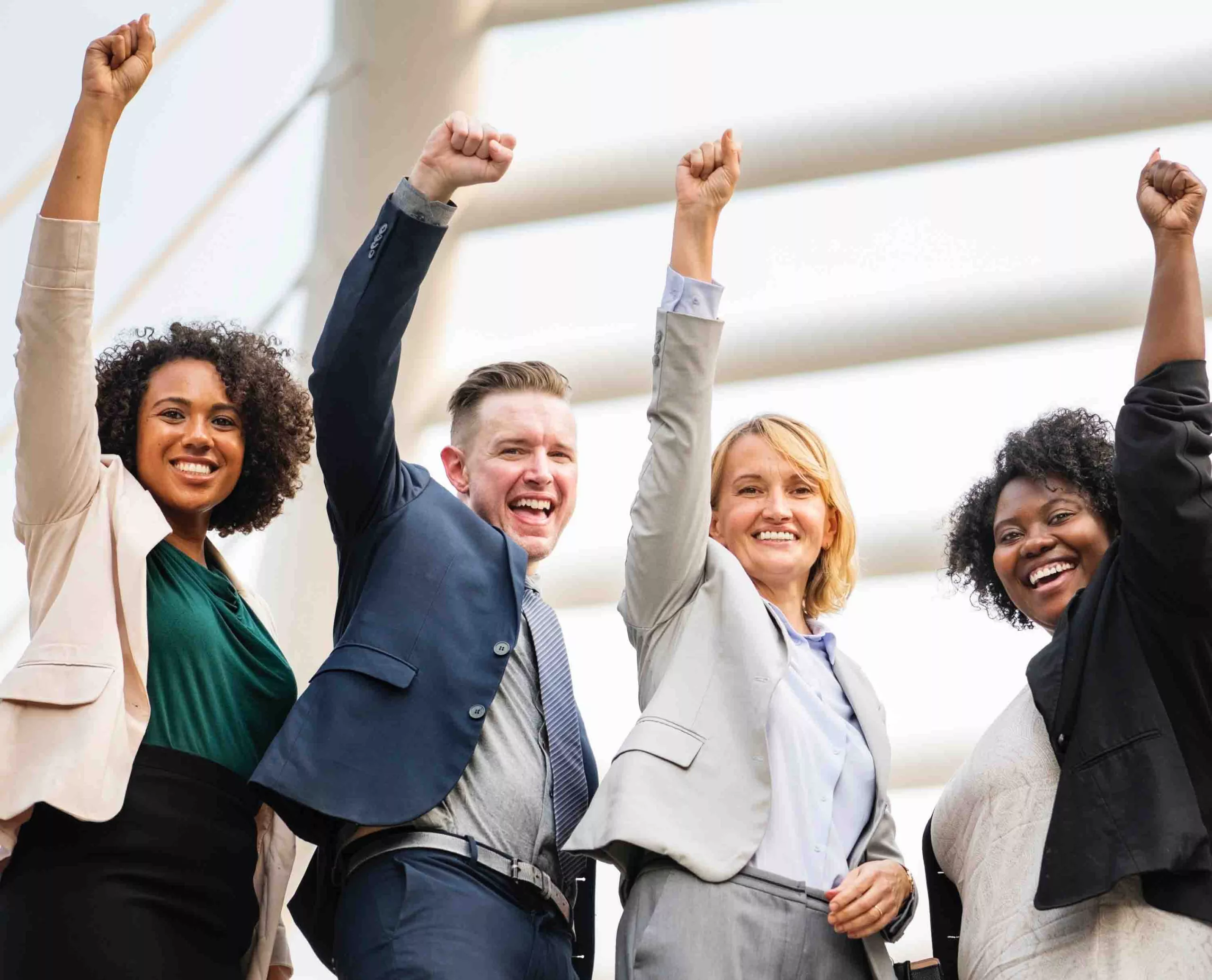 Diverse group of professionals celebrating success with raised arms