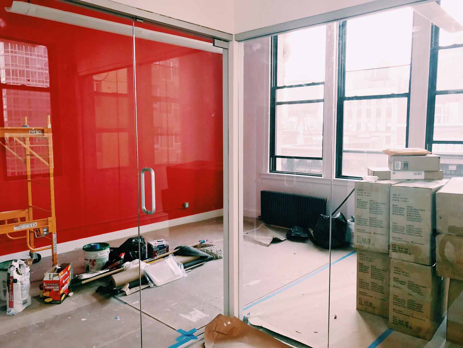 Red accent wall in modern office under construction with glass partition