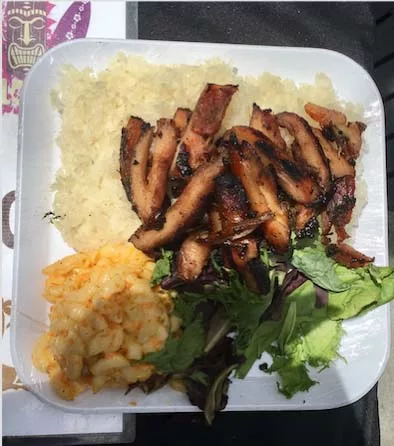 Grilled chicken over rice with side salad and mac and cheese in a takeout container