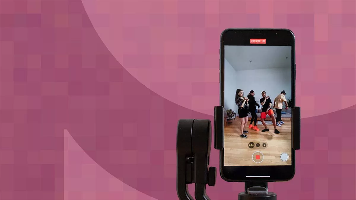 Smartphone recording a dance rehearsal in a studio with pink background.