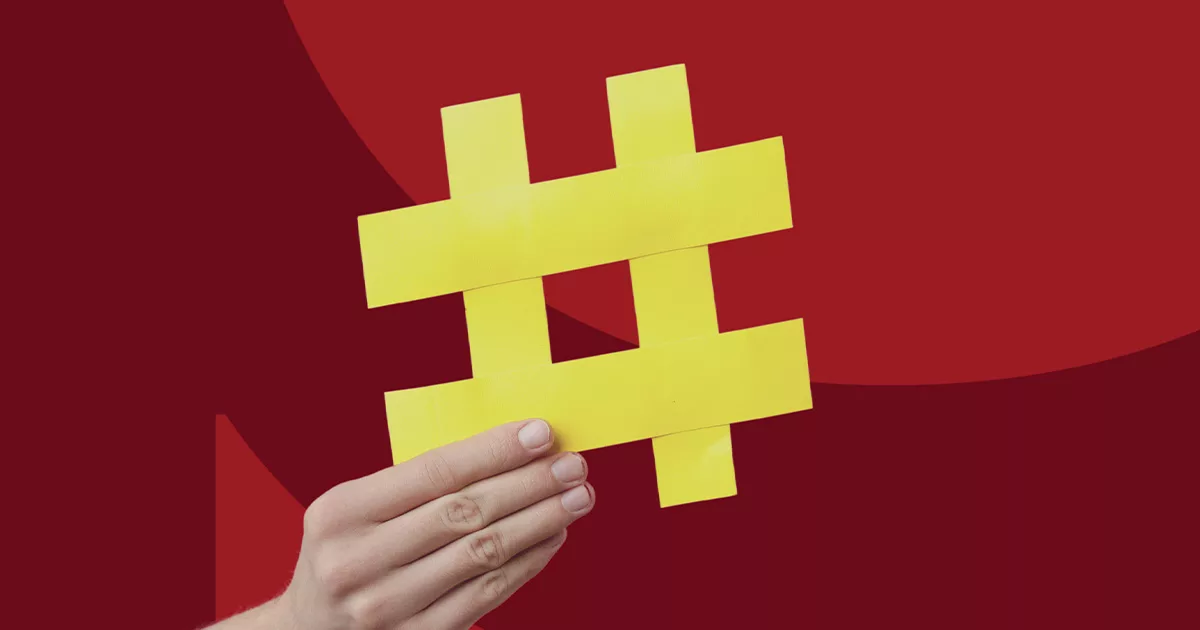 Hand holding yellow hashtag sign against red background