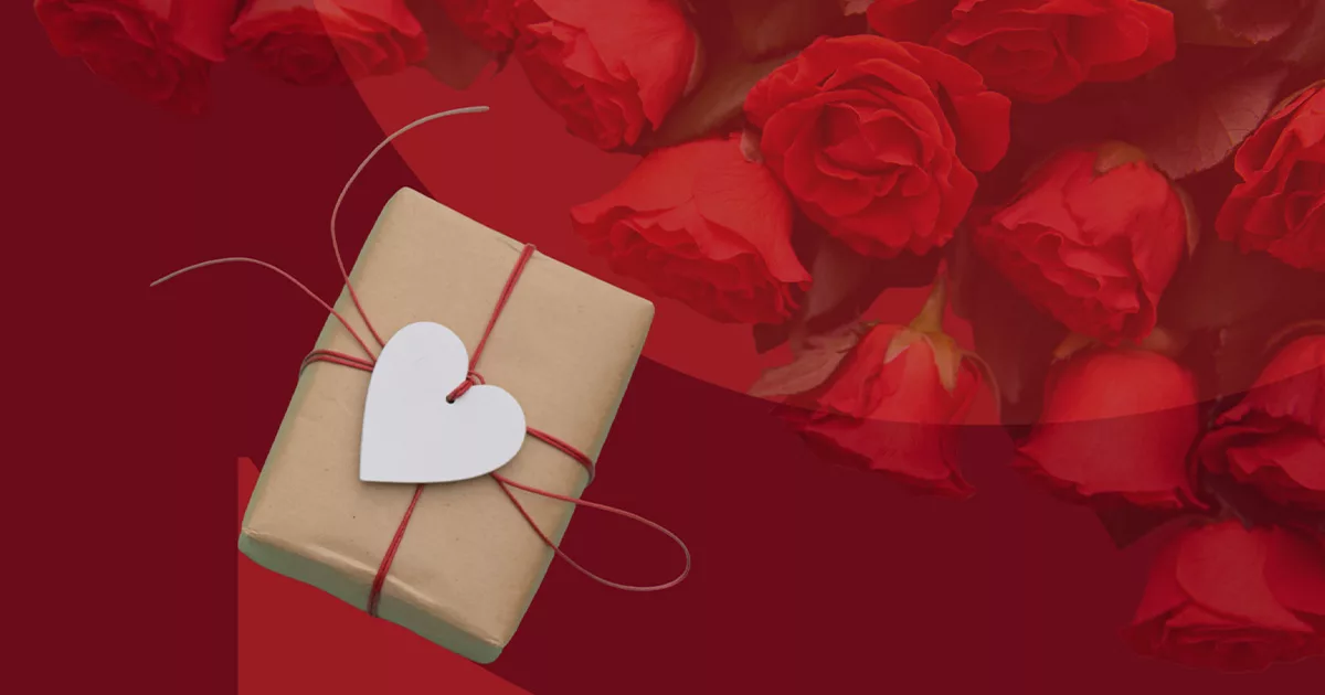 Gift wrapped in brown paper with a white heart tag on a red background with roses.