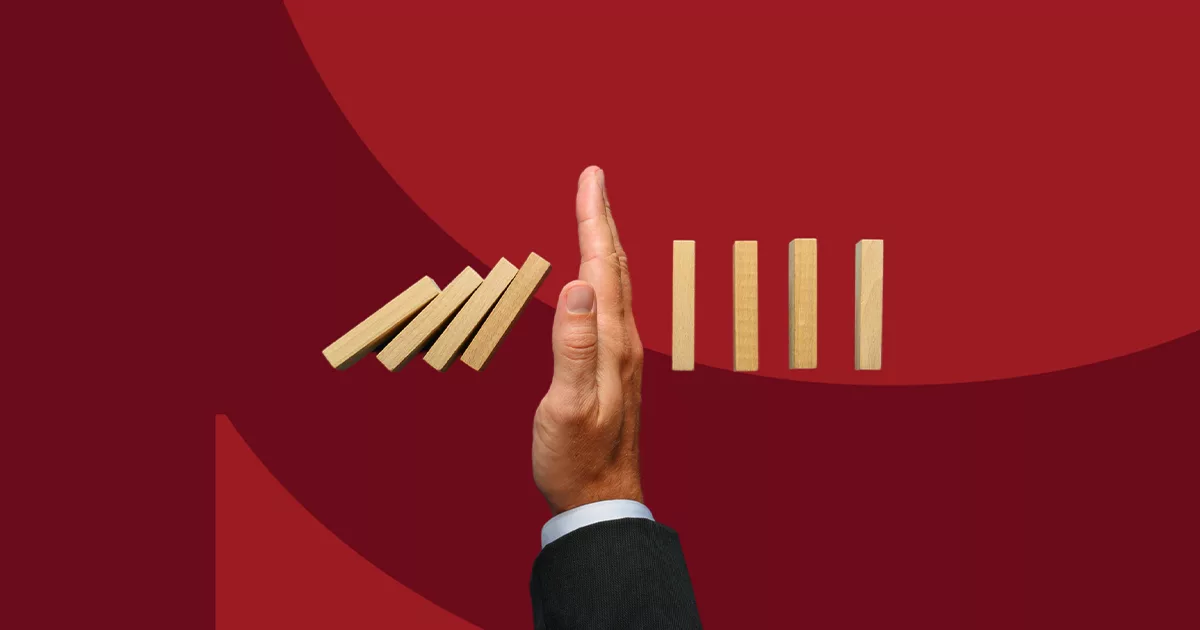 Hand stopping domino effect on red background for problem solving concept
