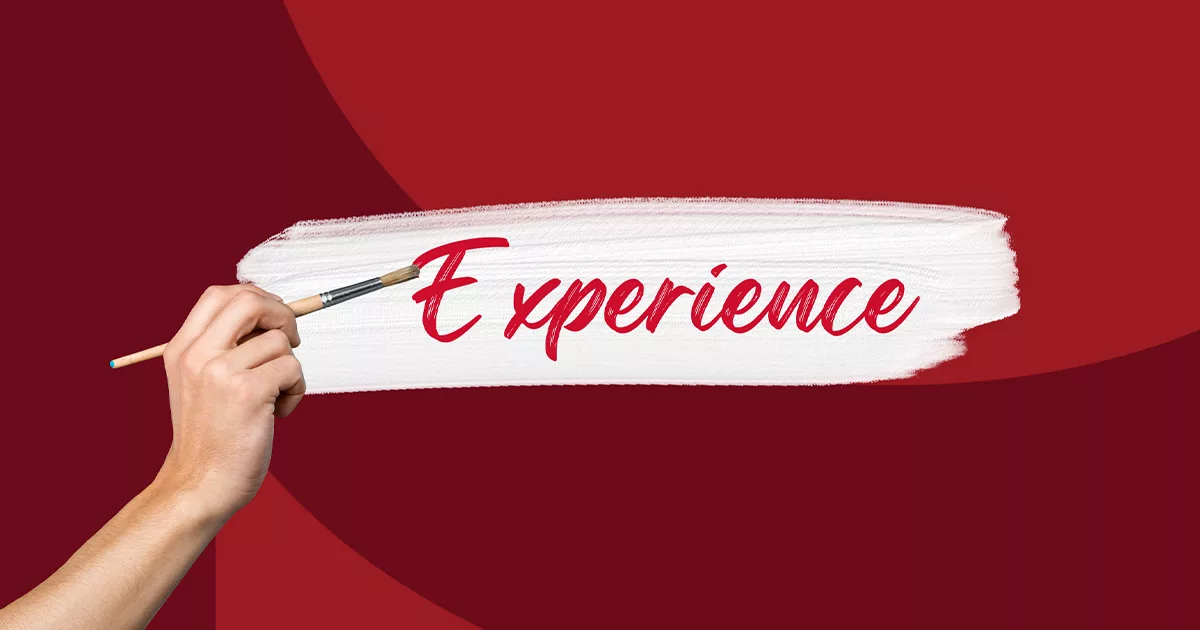 Hand painting the word Experience with a brush on a white streak over a red background