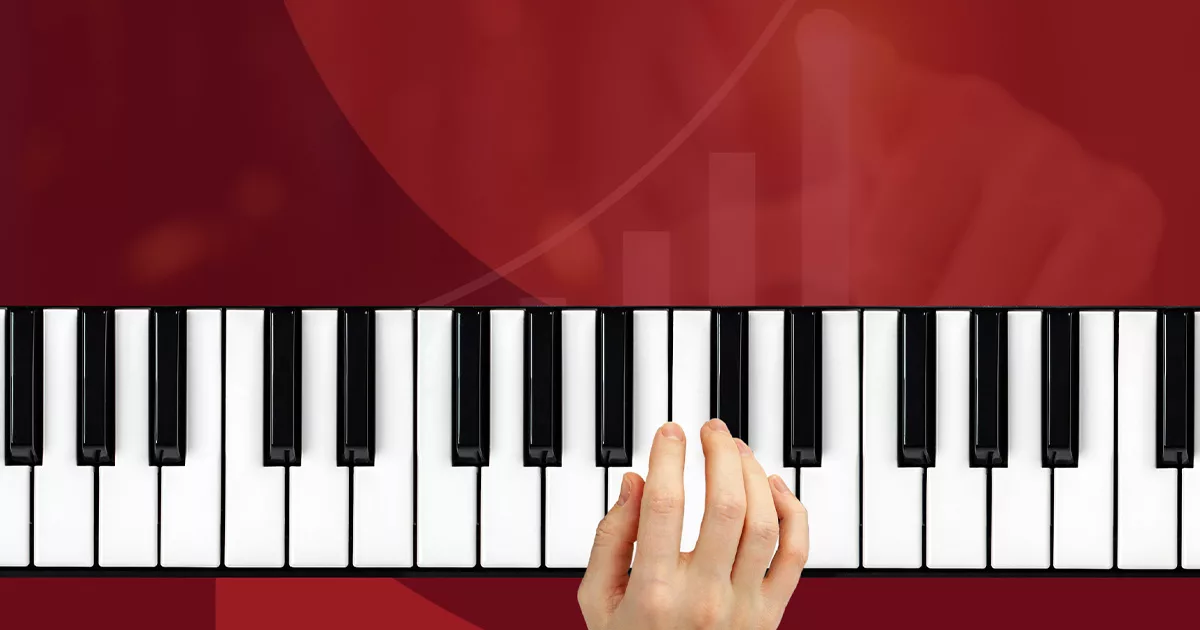 Close-up of hand playing piano keys with red background
