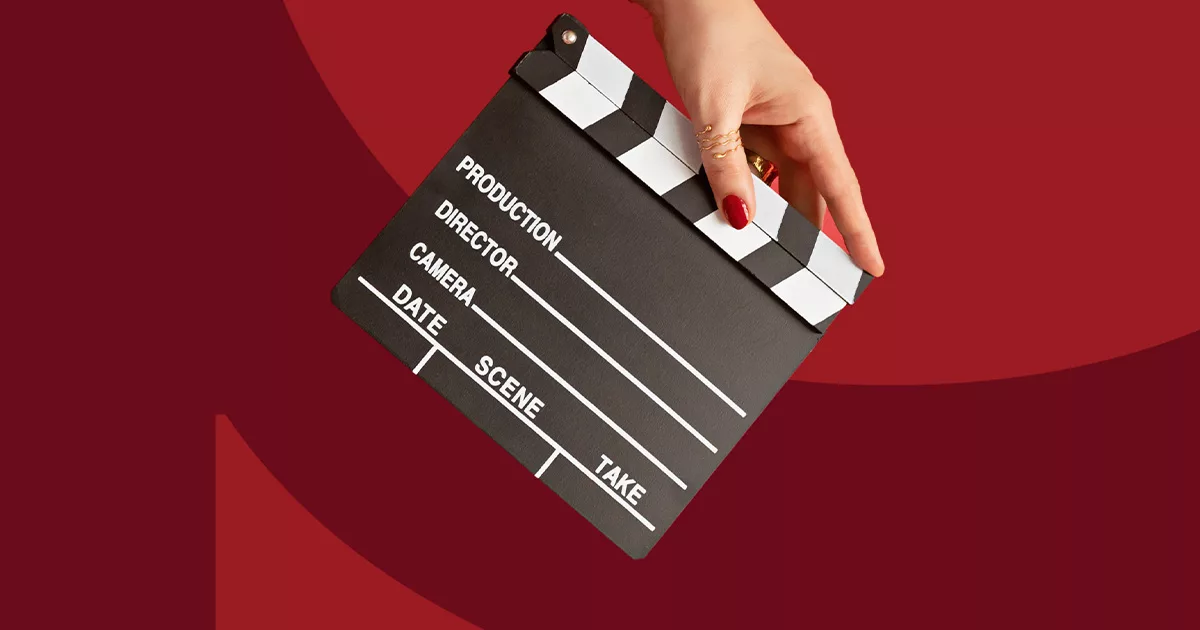 Hand holding a movie clapperboard on a red background