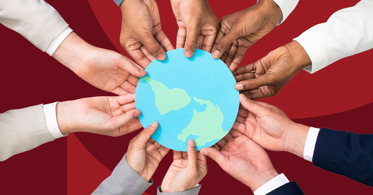 Diverse hands holding a paper cutout of the Earth on a red background.