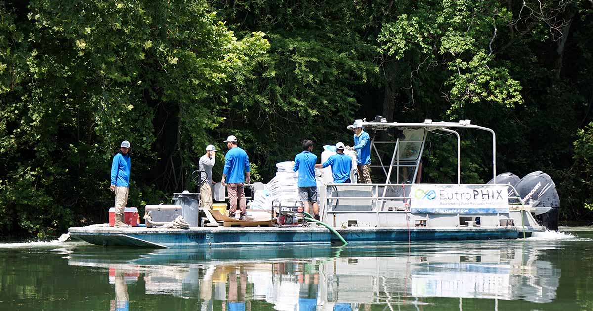 Team of scientists on boat conducting water quality research in forested area