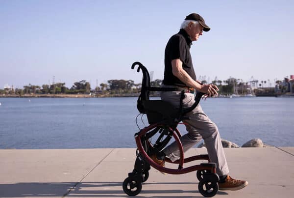 Senior man using a walking aid by the seaside with harbor in the background
