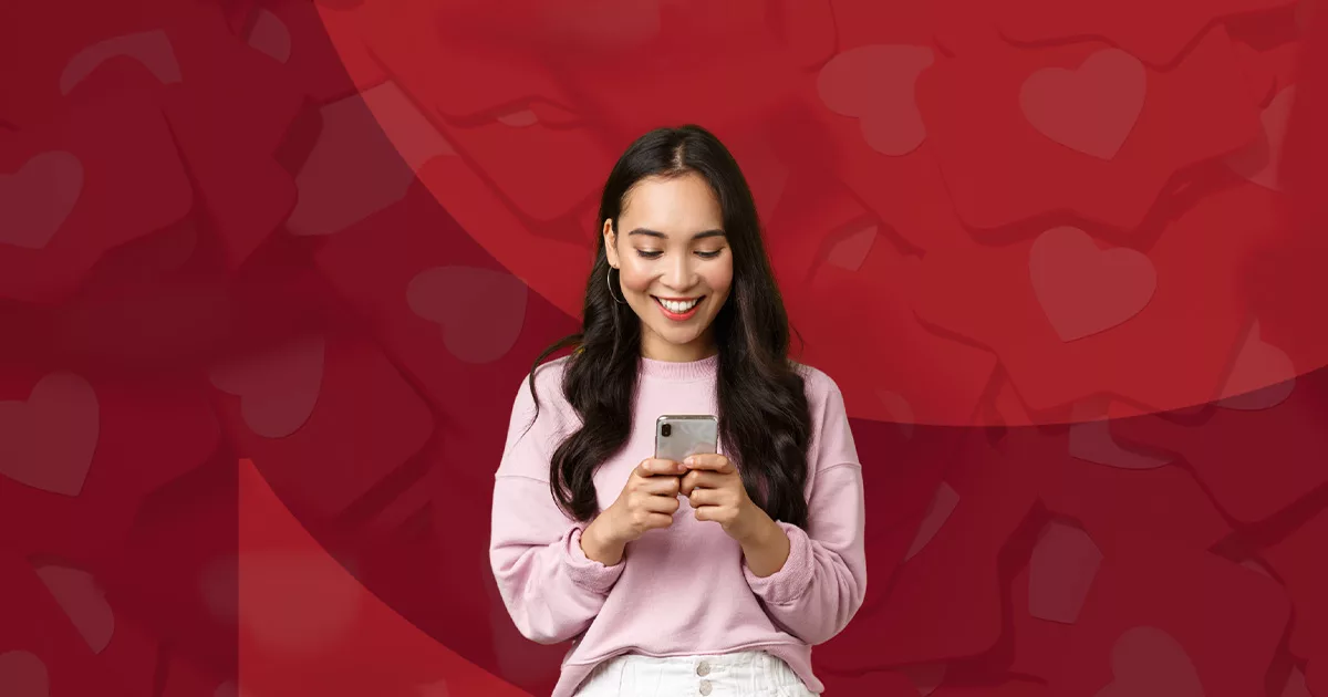 Smiling woman using smartphone against red heart-patterned background