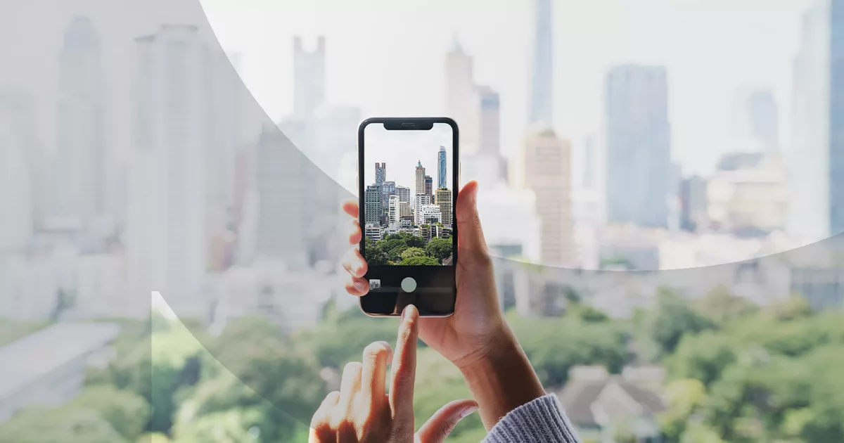 Person holding smartphone capturing city skyline through camera viewfinder
