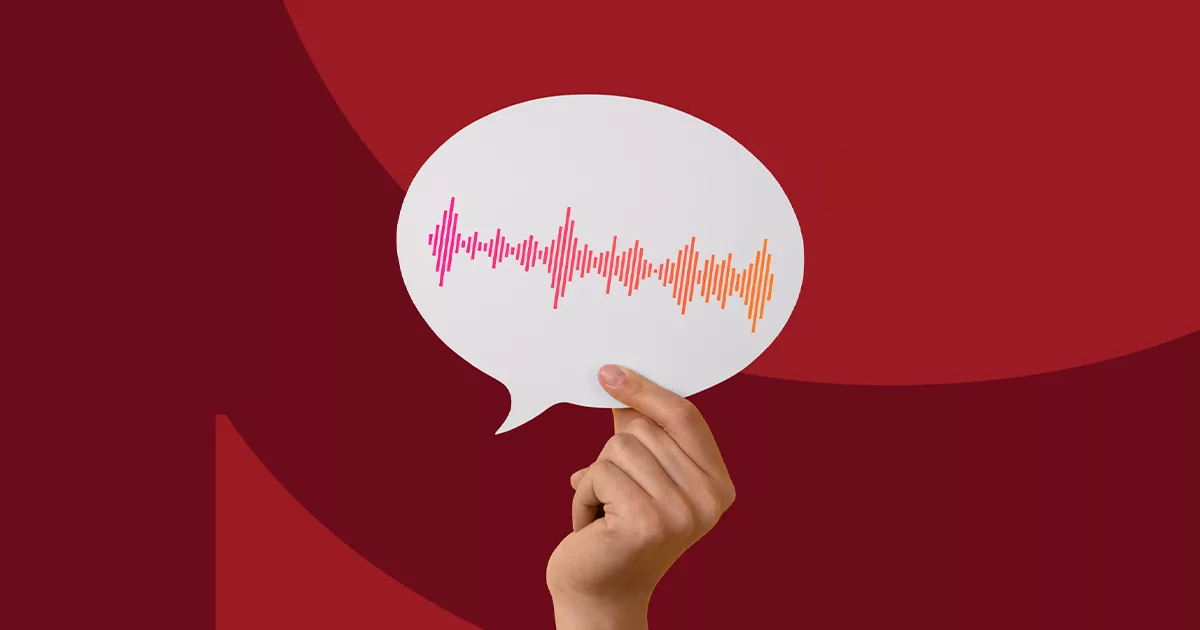 Hand holding speech bubble cutout with sound wave graphic on red background.