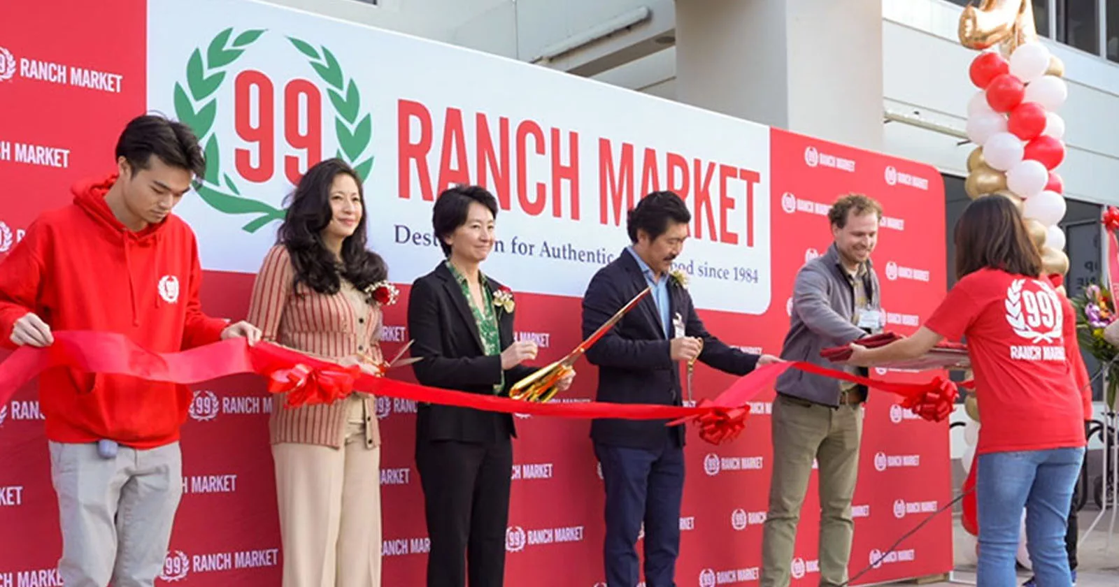 Group of people participating in ribbon-cutting ceremony at new supermarket opening
