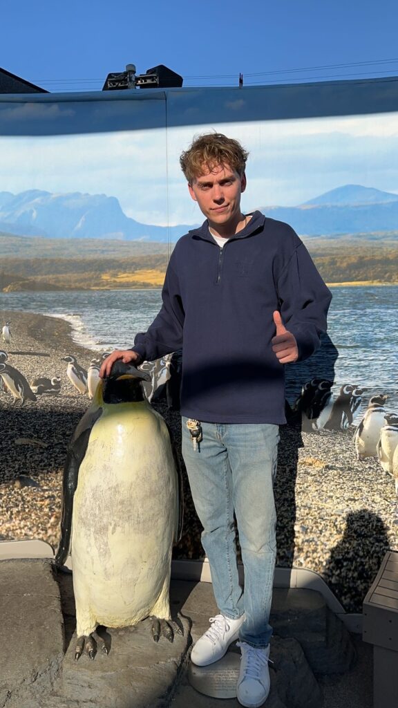 IMG_2559 Man smiling beside a penguin sculpture
