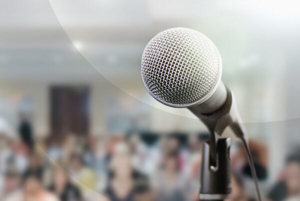 Microphone on a stage in front of a crowded room.