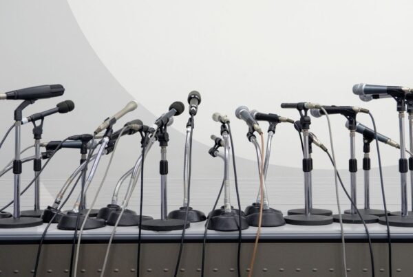 A group of microphones on a podium facing towards a gray background