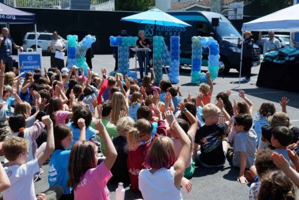 Children sitting down and raising their hands at a Kindness is Free event