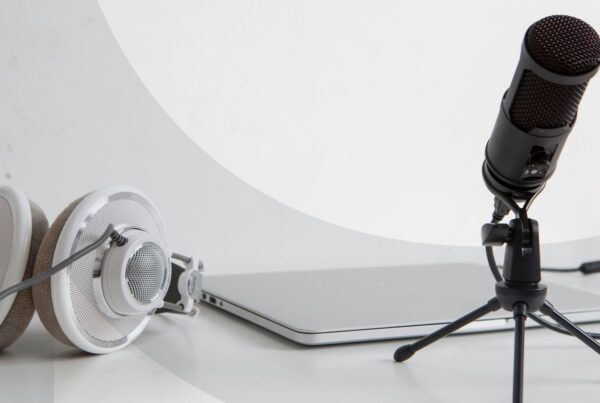 A microphone, laptop, and headset sitting next to each other against a white background.