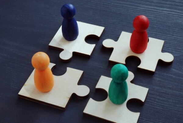 Four jigsaw puzzle pieces with different colored pegs on top of them equally distanced from one another