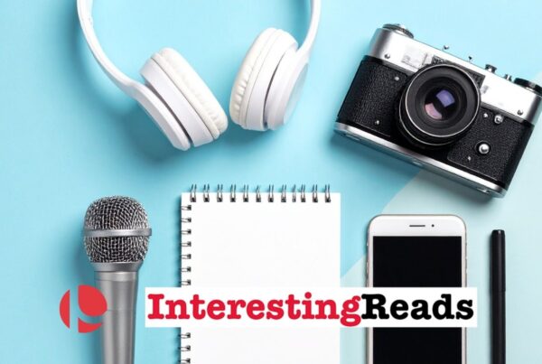 Headphones, a camera, a microphone, a notepad, a cell phone, and a pen laying against a light blue and white background.