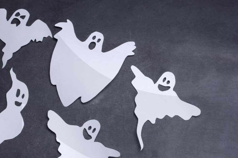 Five cutouts of white ghosts flying against a charcoal background.