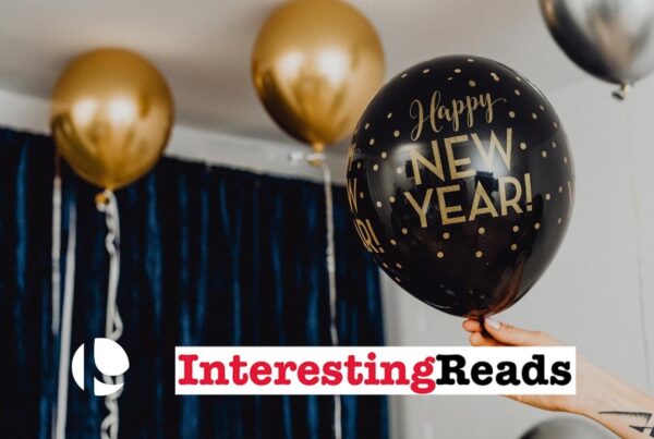 Black and gold balloons that say "Happy New Year" floating to the ceiling in a room