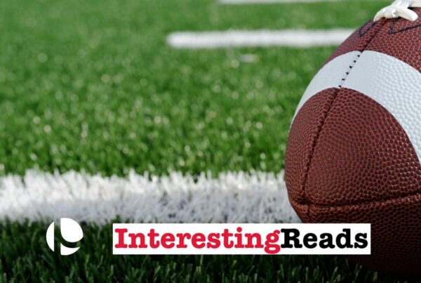 A football on the right side of the foreground resting on a green football field.