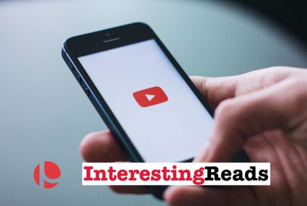 A hand holding a phone with the YouTube logo on the screen.