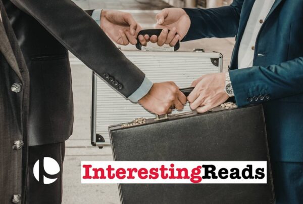 Two men, one in a blue suit and the other in a black suit, exchanging briefcases.