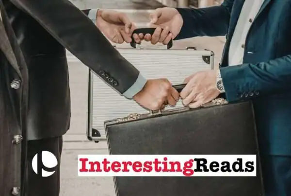 Two men, one in a blue suit and the other in a black suit, exchanging briefcases.
