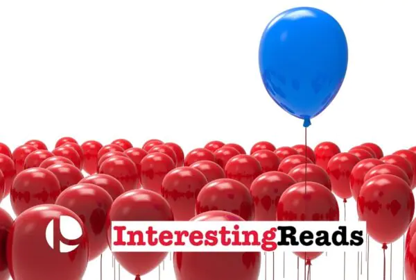 A group of red balloons, and a blue balloon rising from right of center of the red balloon group against a white background.