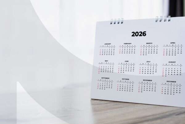 A 2026 calendar propped up on a wooden desk with a window in the background.