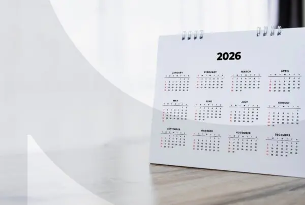 A 2026 calendar propped up on a wooden desk with a window in the background.