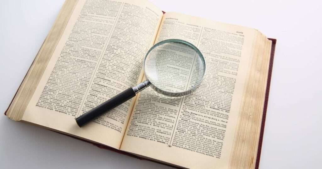 A magnifying glass sitting on top of an open dictionary.