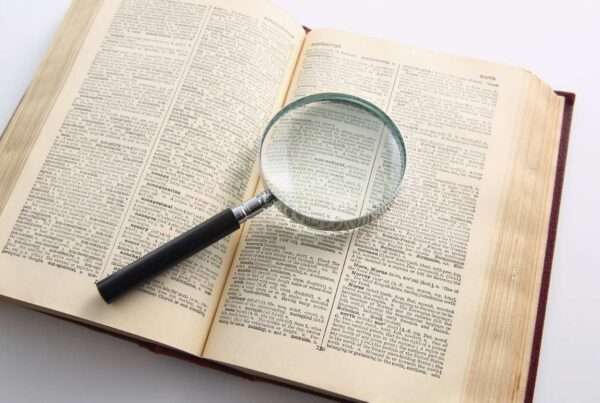 A magnifying glass sitting on top of an open dictionary.
