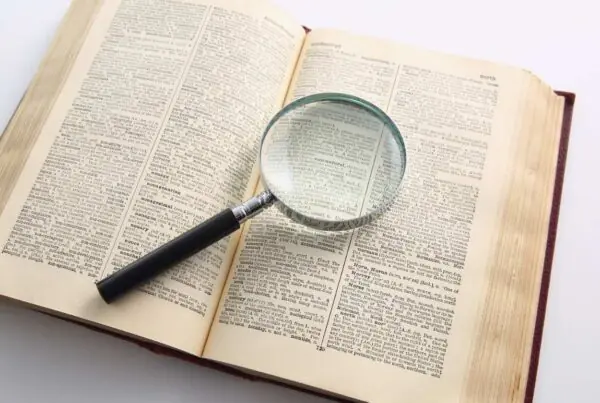 A magnifying glass sitting on top of an open dictionary.